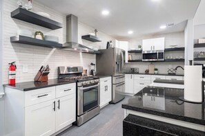 A modern kitchen with white cabinetry, stainless steel appliances, and black countertops. - Bright Dallas Retreat with Fire Pit & Games (Dallas)