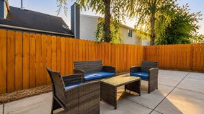 Une terrasse extérieure avec des meubles en osier et une clôture en bois.