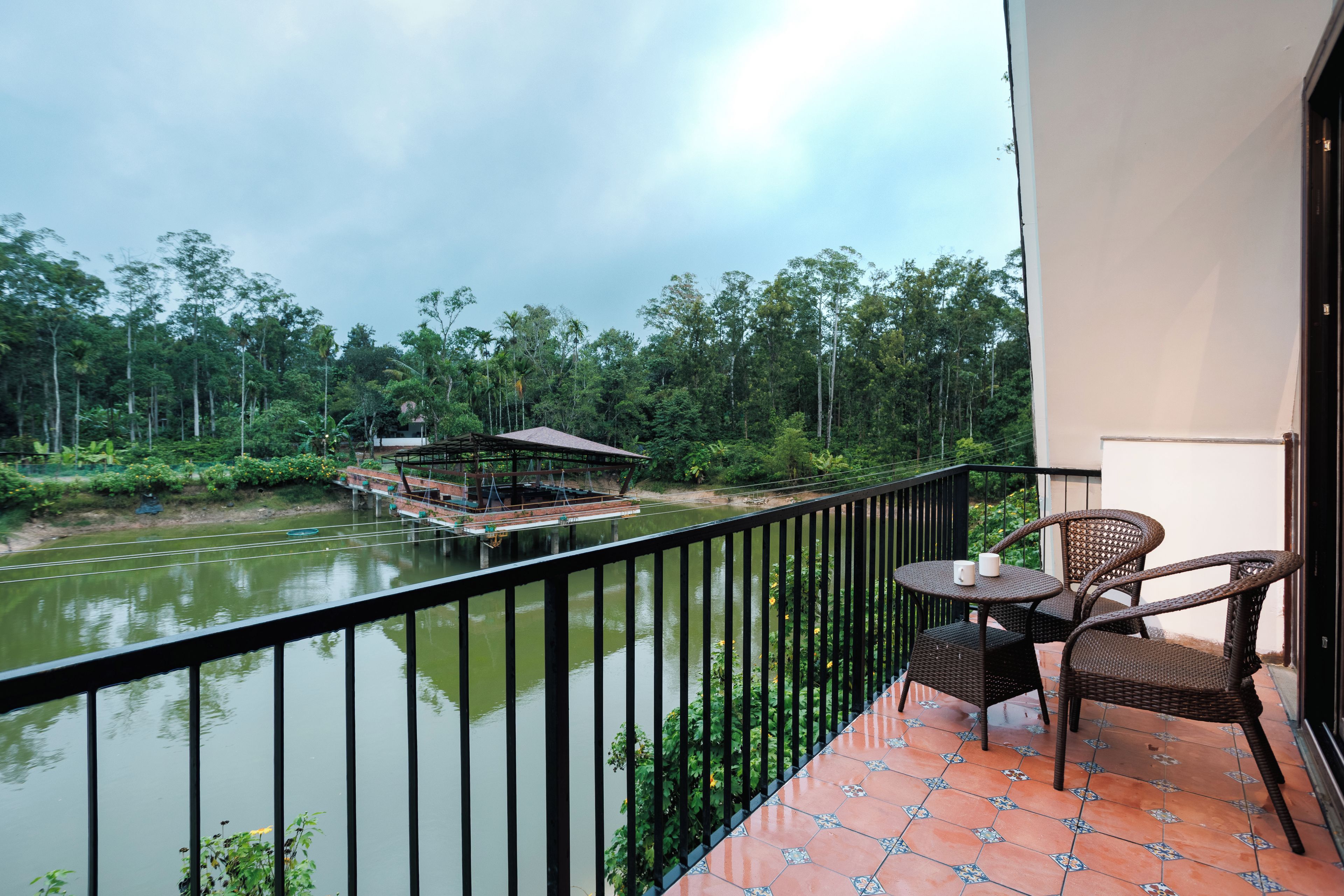 A balcony with a view of a river, a dock, and surrounding greenery.