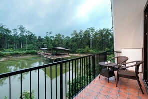 Un balcon donnant sur une rivière, un quai et la végétation environnante.