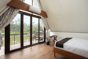 A bedroom with a bed, a chair, and a view of a balcony with a railing and a table. - sai vishram organic village  (Thagare)