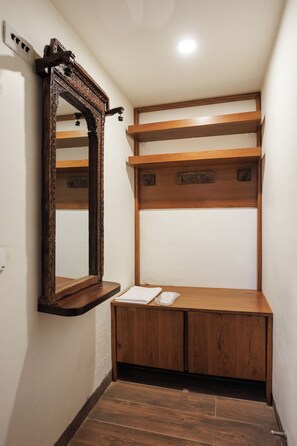 Une salle de bain avec un meuble-lavabo en bois, un miroir doté d’un cadre orné et une étagère au-dessus du meuble-lavabo.