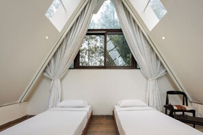 Ein Zimmer mit zwei Betten, einem fenster mit Vorhängen und Blick auf Bäume.