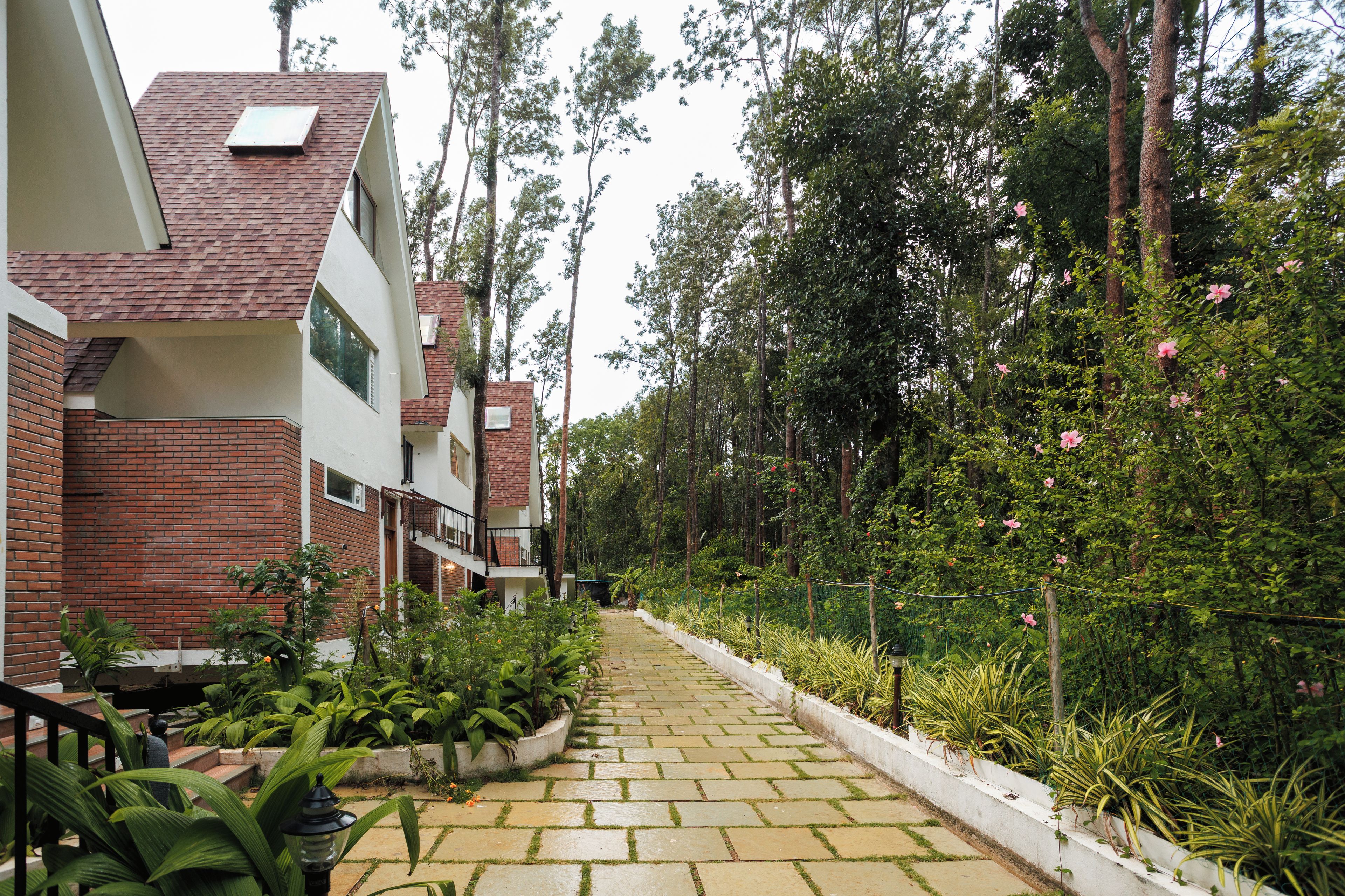 Un sendero conduce a un edificio con fachada de ladrillo y sección superior blanca.