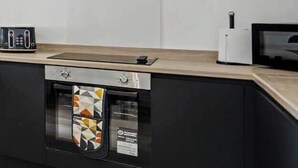 Een moderne keuken met een roestvrijstalen afzuigkap, een inbouwoven en een magnetron.