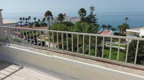 Un balcón con vista a una playa y palmeras.