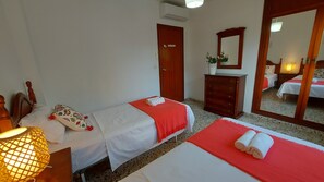 Ein Hotelzimmer mit zwei Betten, einem Holzschrank, einem Spiegel und einer Wand-Klimaanlage.