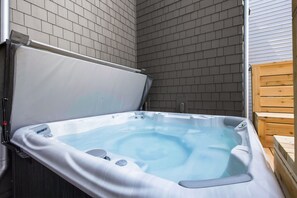 A hot tub with a cover, set against a brick wall.