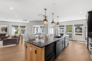 A spacious kitchen with a large island, modern appliances, and pendant lighting. - Seabrook Newhart | Hot Tub, Sauna, Cold Plunge 9BR | Sleeps 18, Garage Parking (Pacific Beach)