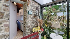 A stone-walled room with a glass door leading to a garden. - View of Château de la Roche-Jagu, Nordic Bath Relaxation Area – Guest Room (Ploëzal)
