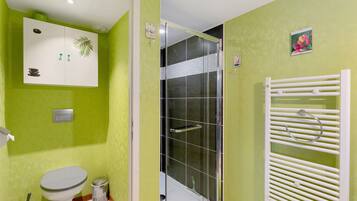 A bathroom with a toilet, a shower, and a sink.