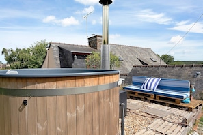 A wooden deck with a bench and a hot tub.