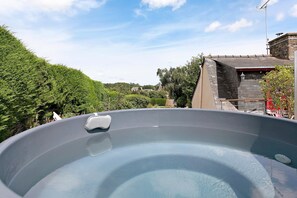 Ein Whirlpool mit Blick auf einen Garten und ein Gebäude mit einer Steinaußenseite.
