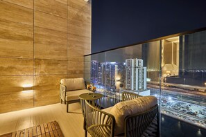 A modern room with a city view, a sofa, a small table, and a chair. - Stylish Studio with Dubai Canal & Skyline Views (Dubai)