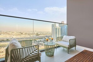 A balcony with a city view, two chairs, a small table with drinks, and a wooden floor. - Stylish Studio with Dubai Canal & Skyline Views (Dubai)