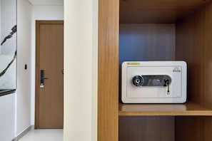 A room with a wooden door, a white wall with a black abstract painting, and a white thermostat on a wooden shelf. - Stylish Studio with Dubai Canal & Skyline Views (Dubai)