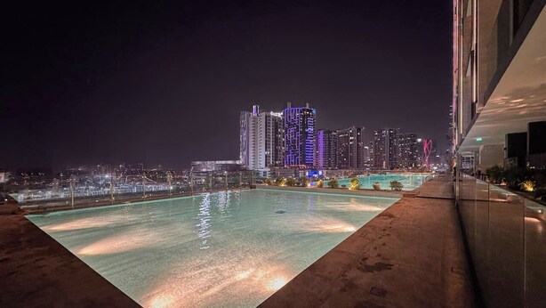 Ein Pool auf dem Dach mit Blick auf die nächtliche Stadtlandschaft.