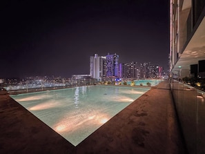A rooftop pool with a cityscape view at night. - Stylish Studio with Dubai Canal & Skyline Views (Dubai)