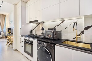 A modern kitchen with a built-in oven, dishwasher, and a coffee machine. - Stylish Studio with Dubai Canal & Skyline Views (Dubai)