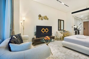 A modern hotel room with a flat-screen TV, a sofa, a dining area, and a mirror. - Stylish Studio with Dubai Canal & Skyline Views (Dubai)