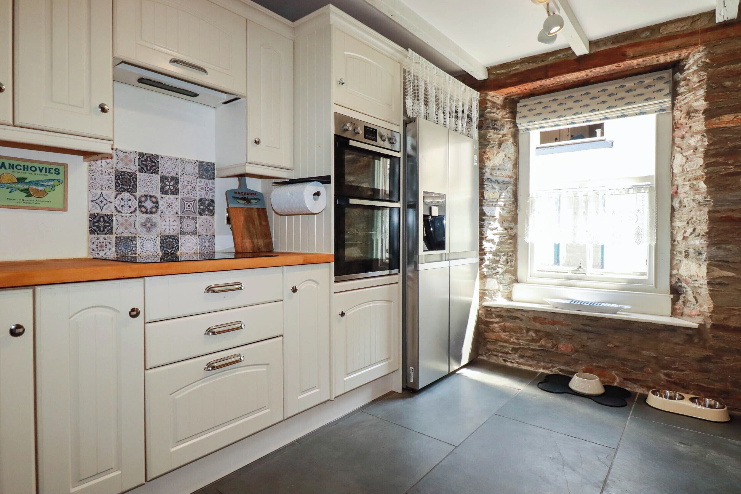 Una cocina con gabinetes blancos, un refrigerador de acero inoxidable y un salpicadero de azulejos.