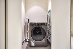 Ett kompakt och modernt tvättrum med en tvättmaskin med frontmatning och en torkställning.