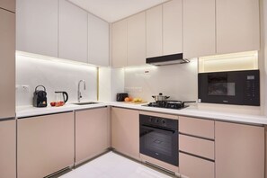 A modern kitchen with a built-in oven, a microwave, and a gas stove. - Modern 1BR | Golf Views | Vista Dubai Sports City (Dubai)