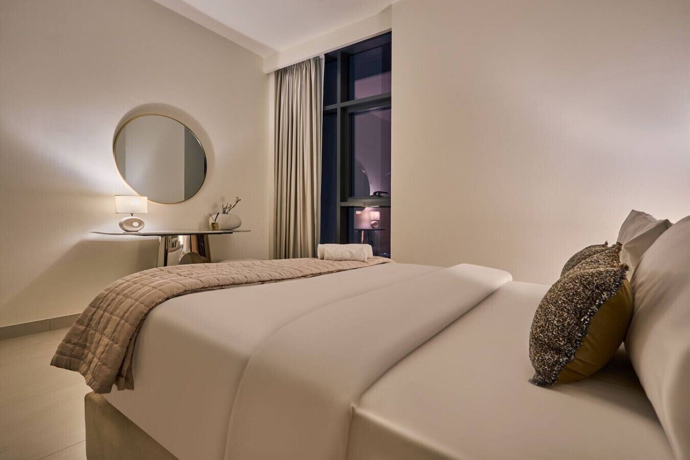 Une chambre d’hôtel avec un lit, une table de chevet, une lampe et une grande fenêtre avec des rideaux.