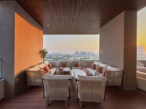 A rooftop lounge with a city view, featuring a mix of seating arrangements and a central table. - Modern 1BR | Golf Views | Vista Dubai Sports City (Dubai)