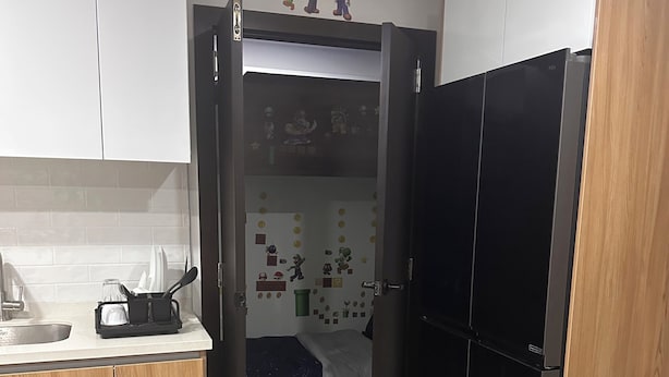Eine kleine Küche mit Kühlschrank, Spüle und einem Bett mit Wandbild.