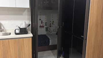 Une cuisine compacte équipée d’un réfrigérateur, d’un évier et d’un lit agrémenté d’une décoration murale.