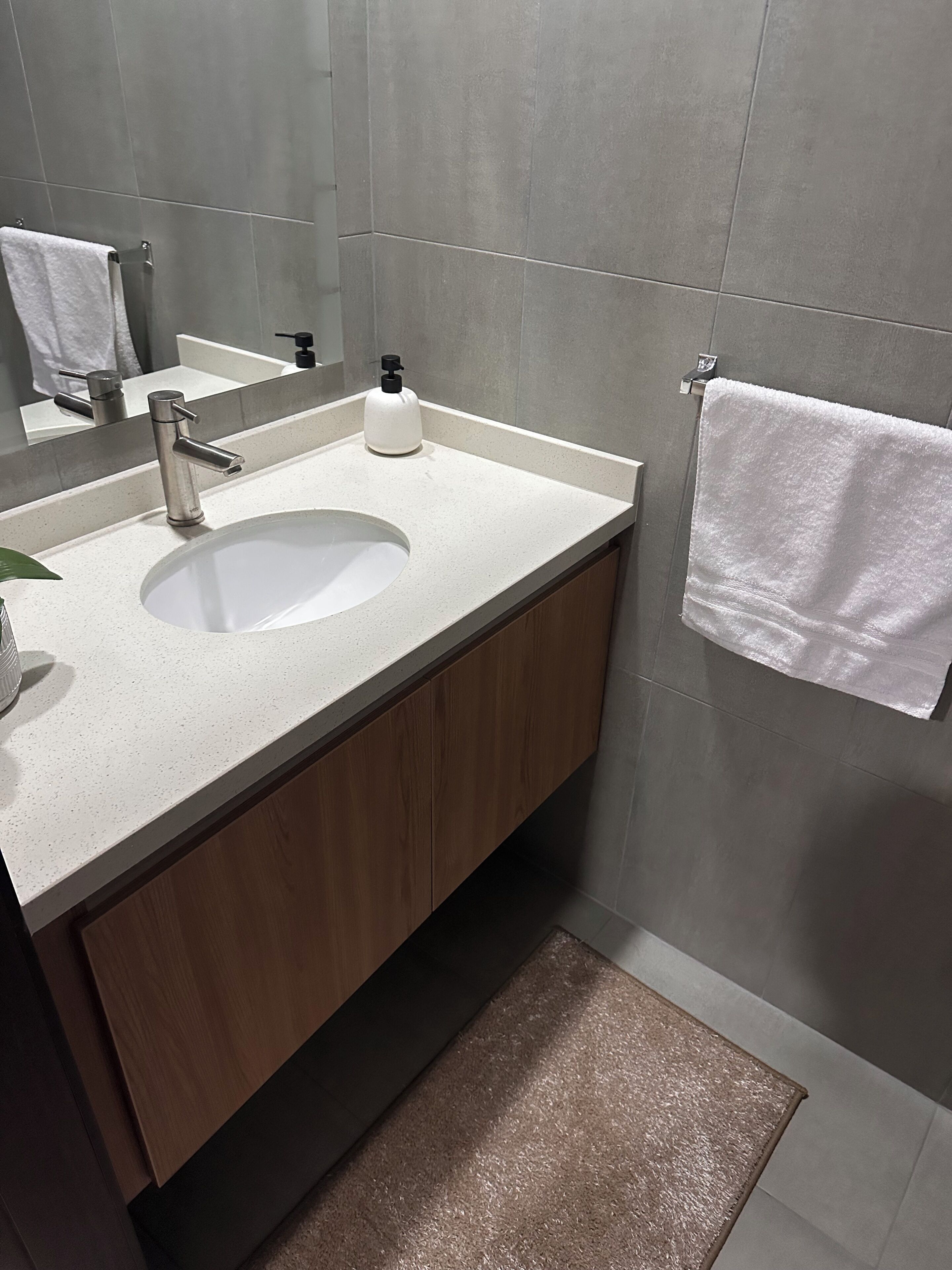 Un baño moderno con un lavamanos blanco, un espejo y un perchero para toallas.