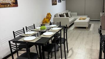 Un coin repas avec une table dressée pour quatre personnes, un canapé et une statue de lion décorative.