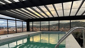 Ein Innenpool mit Blick auf eine Stadtkulisse durch große Fenster.