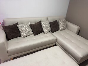 A sectional sofa with a matching ottoman, patterned pillows, and a plain wall in the background. - Fantastic 2-bedroom apartment in Cuenca Kid Bunk Room, private parking and pool (Cuenca)