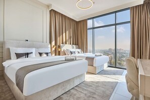 A modern hotel room with a large bed, a smaller bed, a desk, and a view of the city. - Top Floor 2BR | Golf View | Vista Sports City (Dubai)