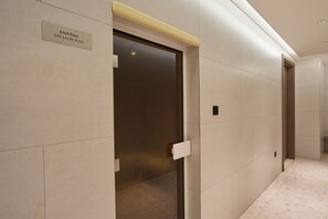 A corridor with a door labeled 'STEAM ROOM' and a light fixture above it. - Top Floor 2BR | Golf View | Vista Sports City (Dubai)
