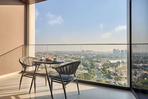 A balcony with a table and chairs, overlooking a cityscape. - Top Floor 2BR | Golf View | Vista Sports City (Dubai)
