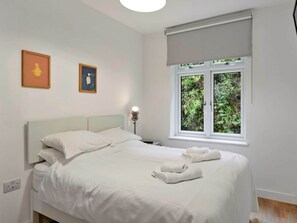 A neatly made bed with white linens, a bedside lamp, and two framed pictures on the wall. - Riverside Cottage With Estuary Views (Fowey)