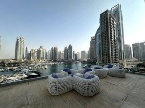 A rooftop terrace with outdoor seating and a marina view. - Stunning 1-Bedroom Apartment | Full Marina View (Dubai)
