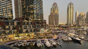 Una marina con numerosi yacht ormeggiati, circondata da edifici residenziali e una zona lungomare ben illuminata.
