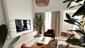 Un soggiorno moderno con televisore a schermo piatto, una poltrona, un tavolino da caffè e una poltrona rossa.