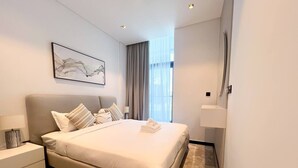 Una habitación de hotel moderna con una cama grande, una mesita de noche, una lámpara de pared y una ventana con cortinas.
