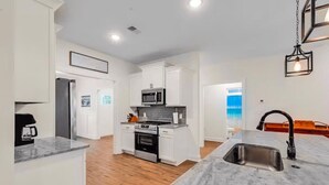 A modern kitchen with white cabinetry, a stainless steel sink, and a built-in oven. - New Home 3-bed 3-bath w/pool, golfcart and bounce house (North Myrtle Beach)