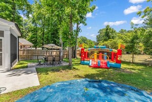 Ein Garten mit Trampolin, überdachter Terrasse und Holzzaun.