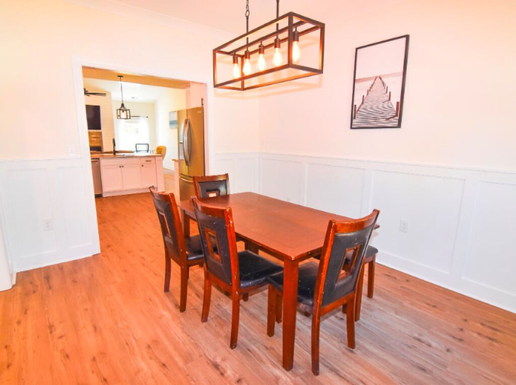 Un coin repas avec une table et des chaises en bois, un luminaire suspendu et un tableau encadré au mur.
