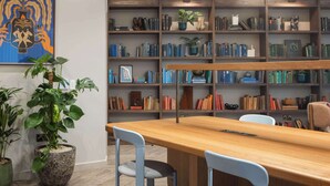 Una biblioteca con estanterías, una mesa de madera y dos sillas.