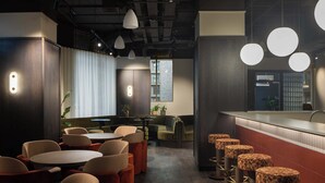 Un interior moderno con mesas redondas, asientos acolchados, iluminación colgante y una zona de bar.
