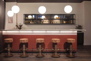A bar area with a long counter, multiple stools, and pendant lighting. - Accessible Studio | Long Stay Ideal | StayCozy (London)