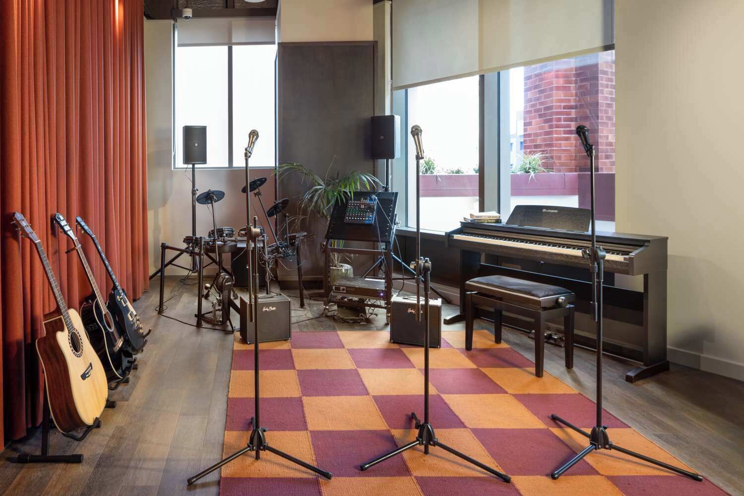 A music room with a grand piano, various guitars, a drum set, and a mixing console.